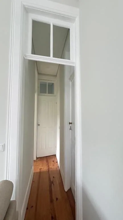 Corredor com chão de madeira e portas brancas